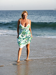 Kelly strolls on the beach in a white bikini and gets wet.